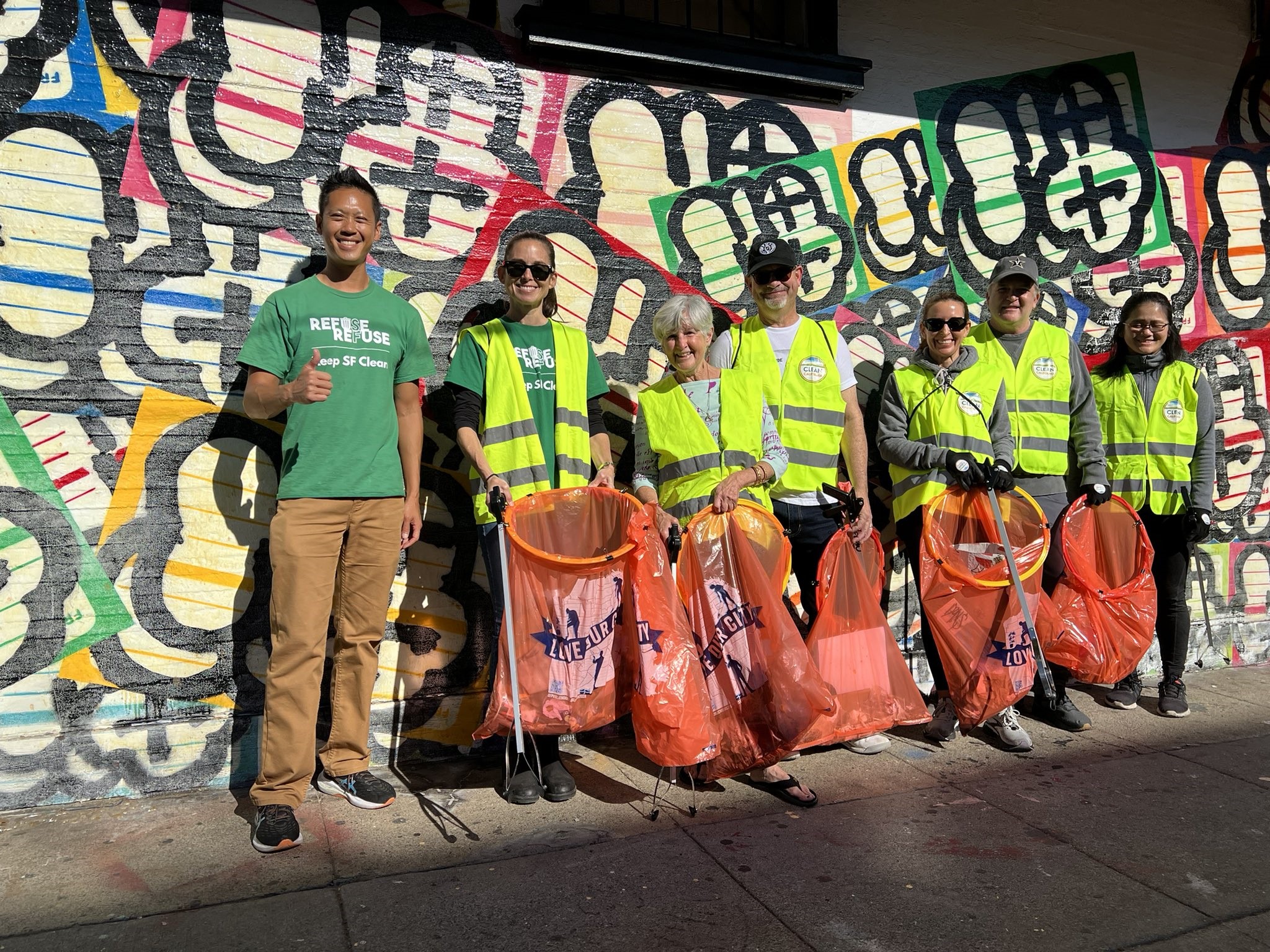 Group photo of volunteers with litter grabbers and trash bags during a community cleanup event.